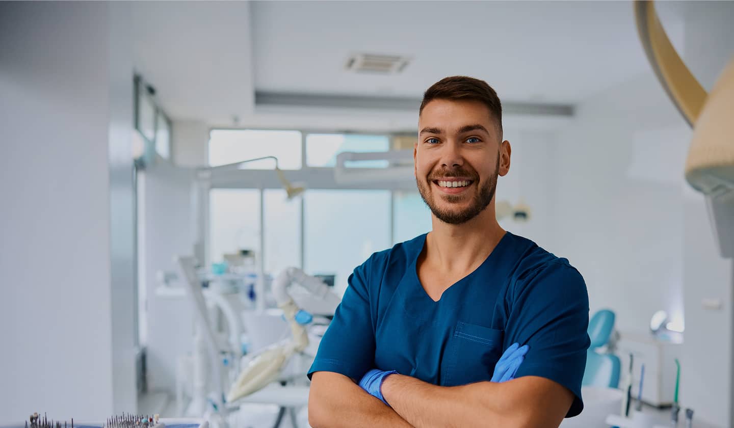 dentist in scrubs and gloves smiling