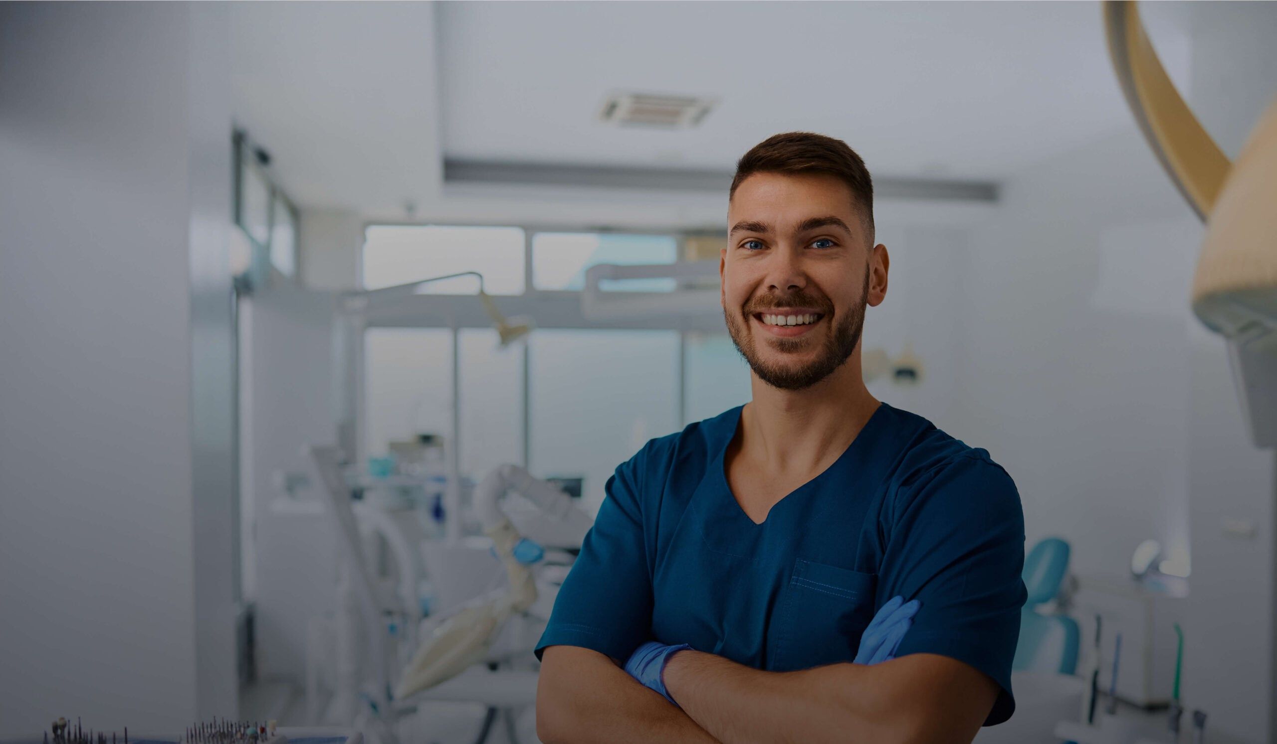 dentist in scrubs and gloves smiling