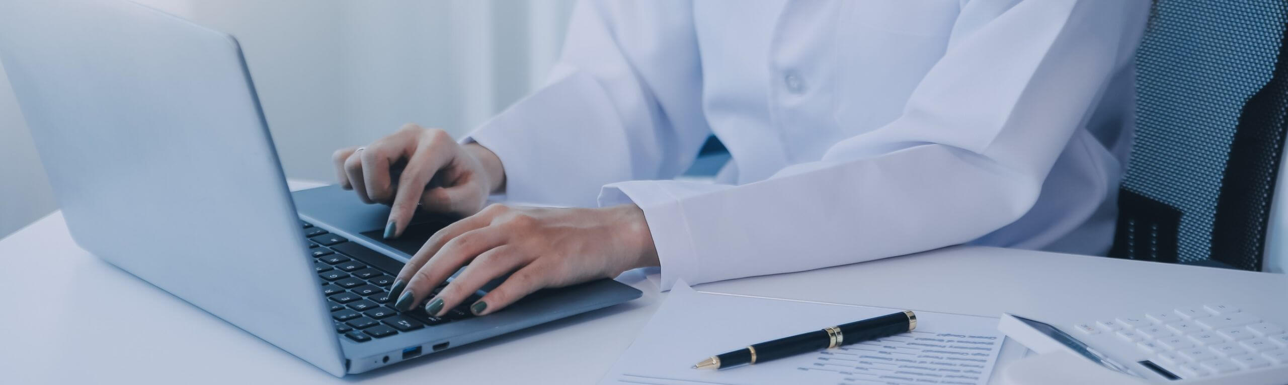 Dentist typing on a laptop at a desk
